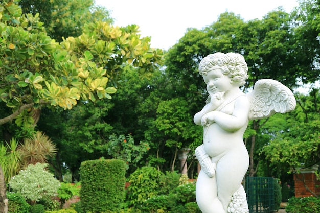 Adorabile scultura di cupido cattivo nel giardino estivo