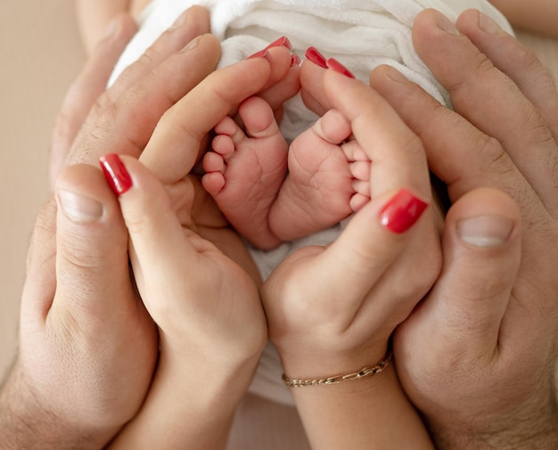 Adorable newborn baby child feet in hands of mother and father closeup parents care about cute tiny