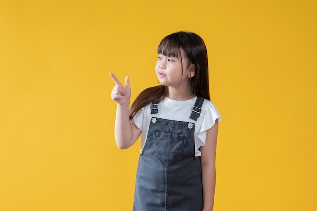 An adorable and positive little asian girl is looking and pointing her finger aside