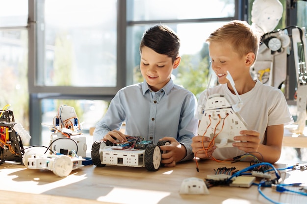 Adorable pre-teen kids inspecting robotic vehicle workshop