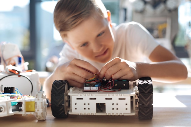 Adorable pre-teen kids inspecting robotic vehicle workshop