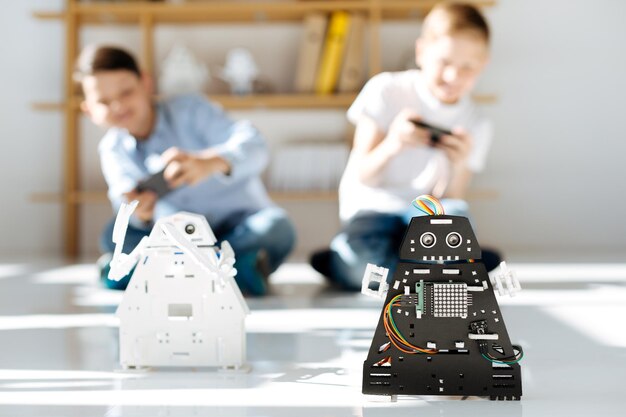 Очаровательные дети предподросткового возраста осматривают мастерскую роботизированных транспортных средств