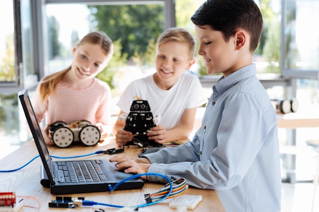 Adorable pre-teen kids inspecting robotic vehicle workshop