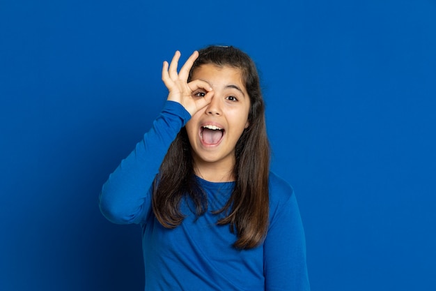 Adorable Preteen girl with blue jersey gesturing over blue wall