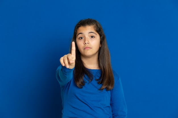 Adorable Preteen girl with blue jersey gesturing over blue wall