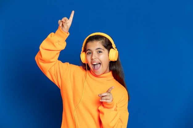 Adorable preteen girl with yellow jersey gesturing over blue wall