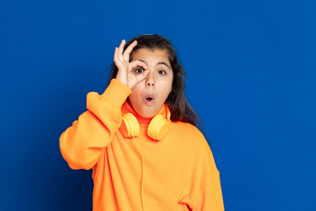 Adorable Preteen girl with yellow jersey gesturing over blue wall