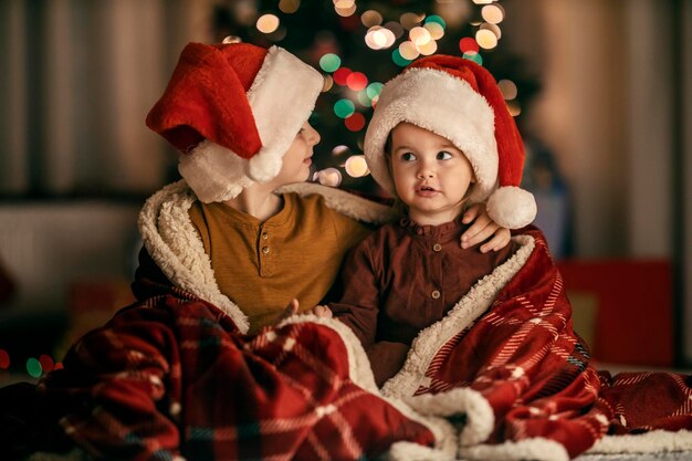 Adorable siblings sharing love and hugging on christmas eve at home