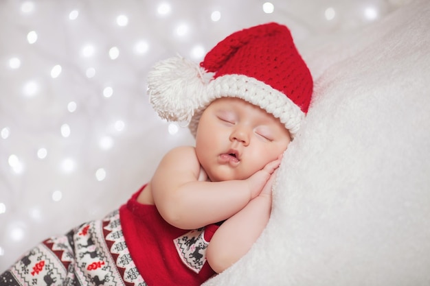 Adorable sleeping newborn baby wearing Santa Claus hat Christmas New Year