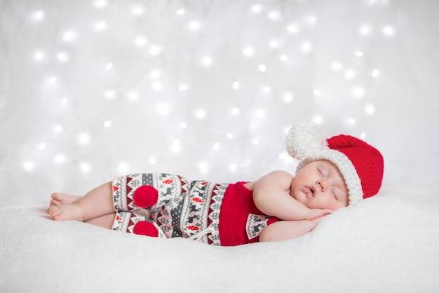 Adorable sleeping newborn baby wearing Santa Claus hat Christmas New Year