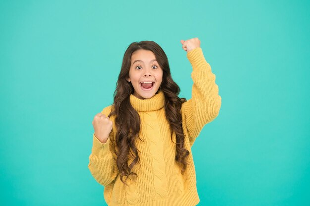 Adorable small girl in cozy fashion style. knitting for kids. Little girl on blue background. Pure beauty of baby girl. Small girl with long brunette hair. Childhood and girlhood. happy childhood.