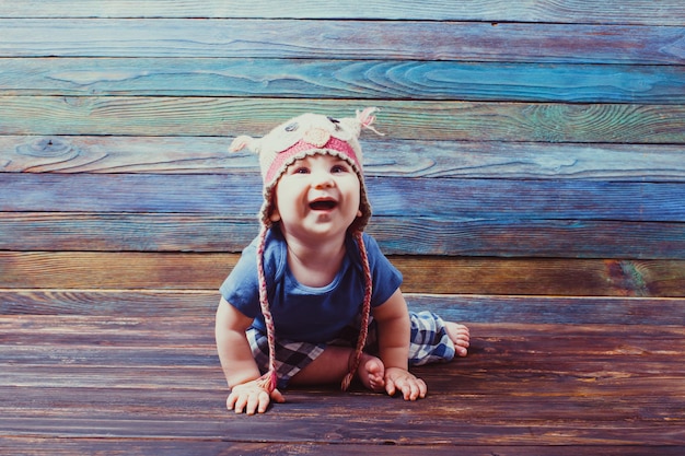 Adorable smiling baby in owl hat, playing on the floor