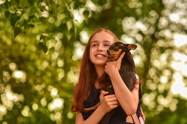 Adorable smiling little girl child schoolgirl holding and playing with pet dog. Best friends.