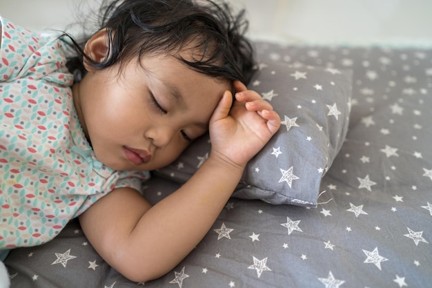 Очаровательный ребенок из Юго-Восточной Азии спит в своей постели