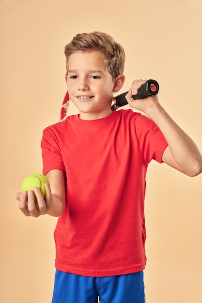 Adorable sporty boy holding tennis racket and ball