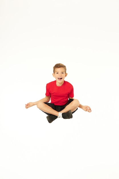 Photo adorable sporty boy jumping and doing yoga exercise