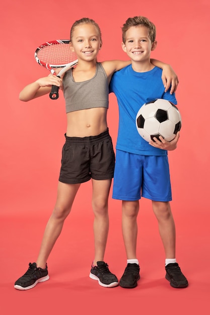 Adorable sporty kids standing against red background