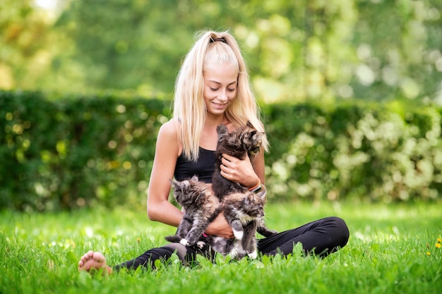 Adorable teenager girl playing with small kittens at warm and sunny summer day