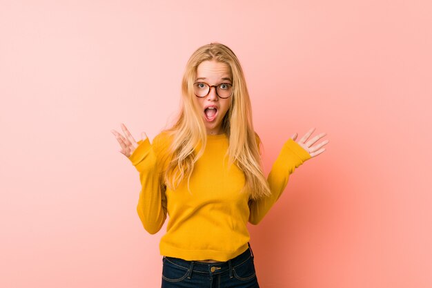 Adorable teenager woman celebrating a victory or success, he is surprised and shocked.