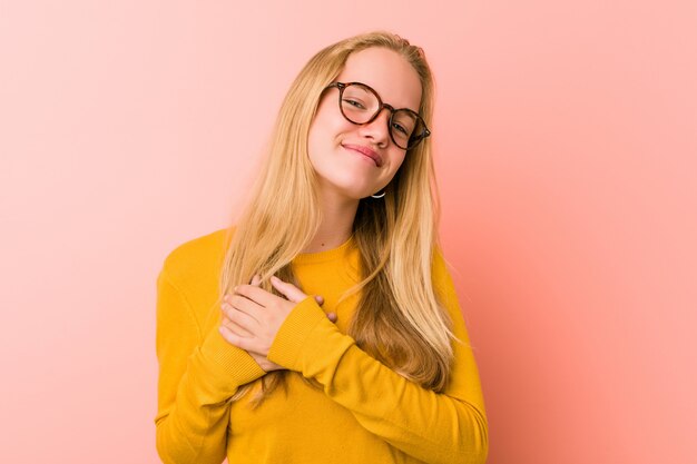 Adorable teenager woman has friendly expression, pressing palm to chest. Love .