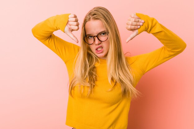 Adorable teenager woman showing thumb down and expressing dislike.