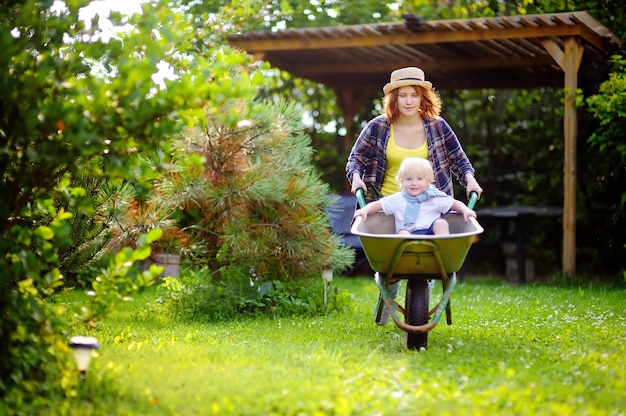 写真 母によって押す手押し車で楽しんでいる愛らしい幼児少年