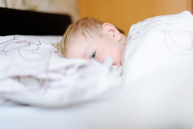 Adorable toddler boy sleeping in a bed