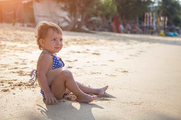 Adorabile bambina che gioca sulla spiaggia sabbiosa dell'isola tropicale