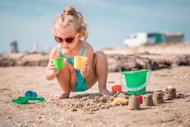 Adorable toddler girl playing on white sand beach