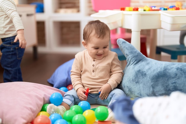 Adorable toddler playing with toys sitting on floor at kindergarten