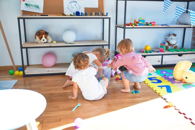 Adorable toddlers playing around lots of toys at kindergarten