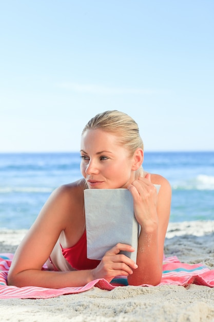 Donna adorabile che legge un libro sulla spiaggia