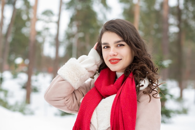 Adorable woman with red lipstick posing in snowy winter. Empty space