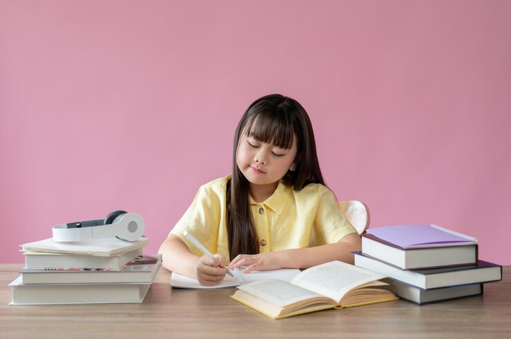 Photo 愛らしいアジアの若い女の子が勉強机で宿題に集中しています