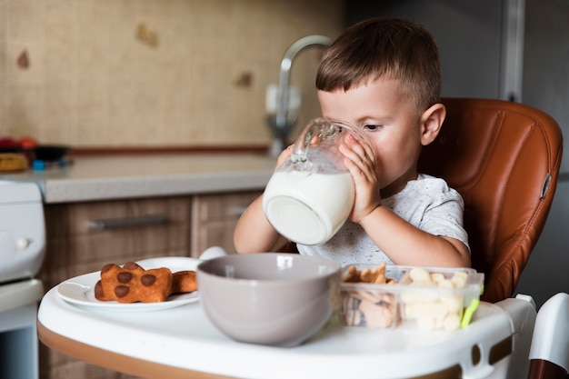 Photo adorable young boy drinking milk