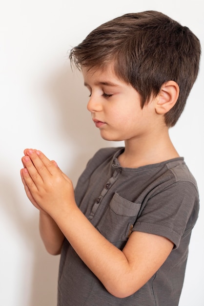 Photo adorable young boy praying at home