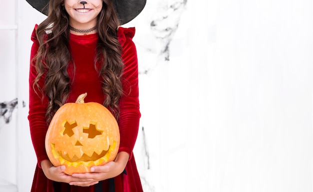 Adorable young girl with carved pumpkin for halloween