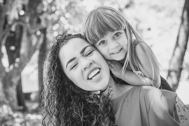 Adorable young mother with her daughter exchanging affection. Mother and daughter in the park. Happy Mothers Day