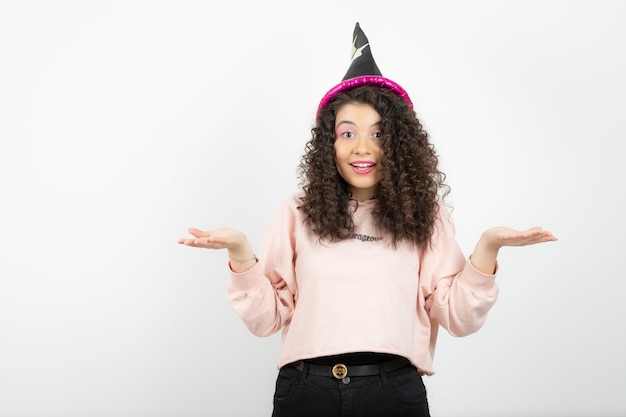 Adorable young woman with curly hair wearing special hat for party.