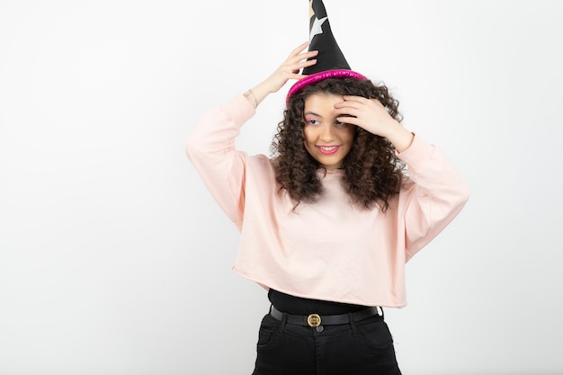 Adorable young woman with curly hair wearing special hat for party.