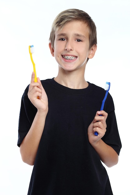 Adorablee boy holding toothbrush and smiling at camera isolated on white