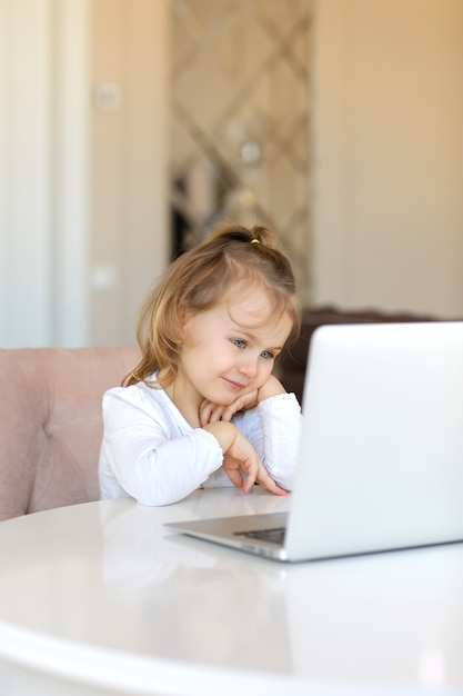 Adorible girl uses a laptop video chat for online communicion at home Child online