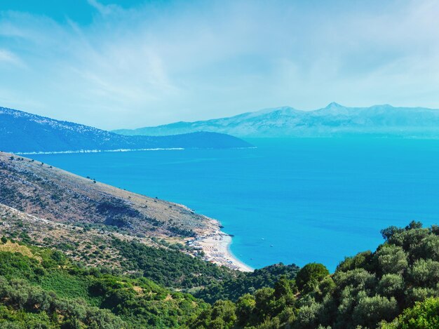 Adriatische zee zomerkust met strand en eiland Corfu in mist Lukove komuna Albanië Uitzicht vanaf bergpas