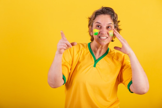 遠くの宣伝写真で何かを指している大人の大人の女性ブラジル サッカー ファン