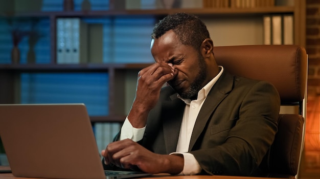 Adult african american businessman working on laptop in office unhealthy tired man suffering