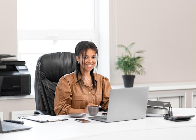 Adult african american businesswoman sitting in office with documents and laptop