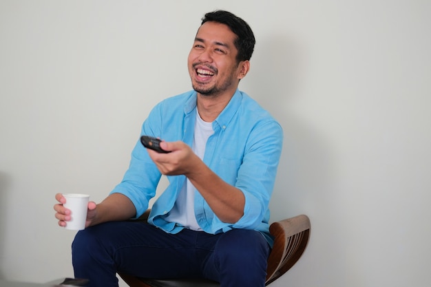 Adult Asian man big laughing when watching television