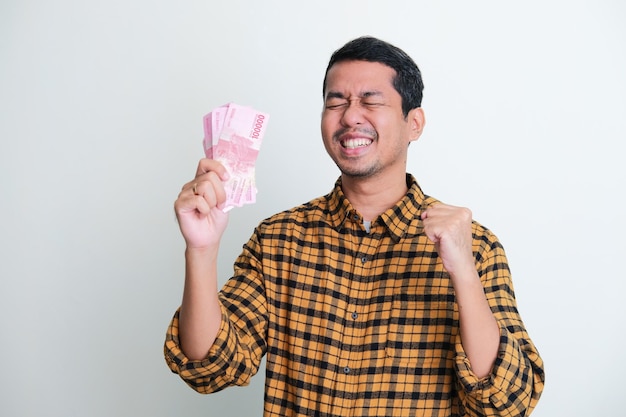 Adult Asian man clenched fist and close his eyes showing happy expression when earn money