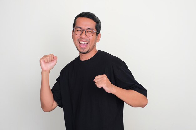 Photo adult asian man dancing happily to celebrate something