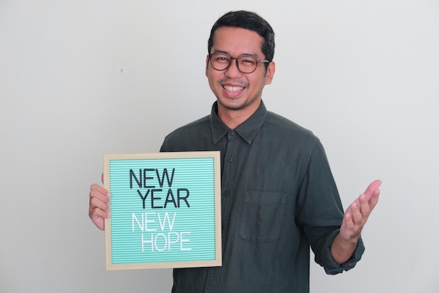 Adult Asian man holding wooden frame with New Year New Hope text
